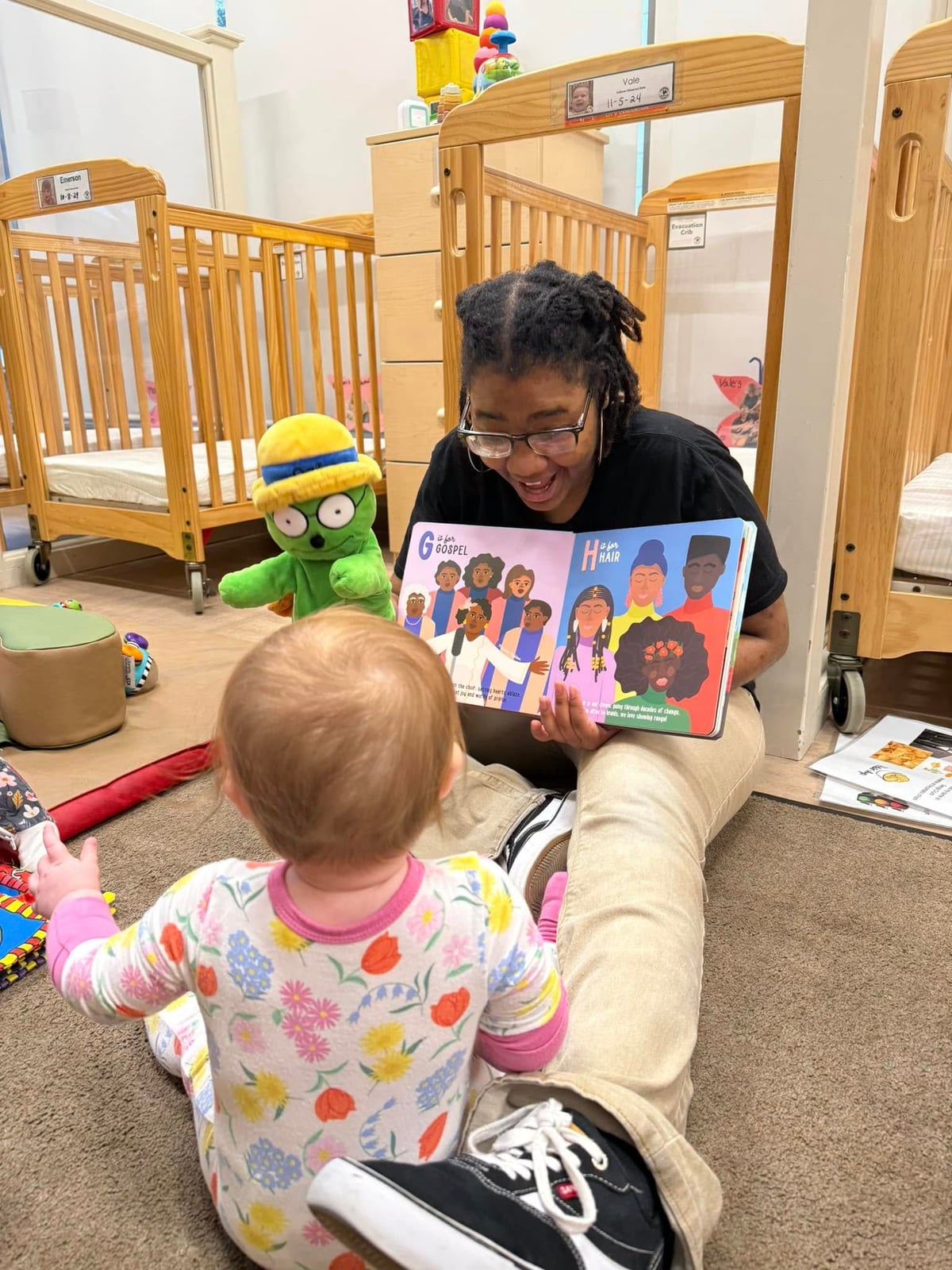 a teacher reading a book to a baby while using a puppet