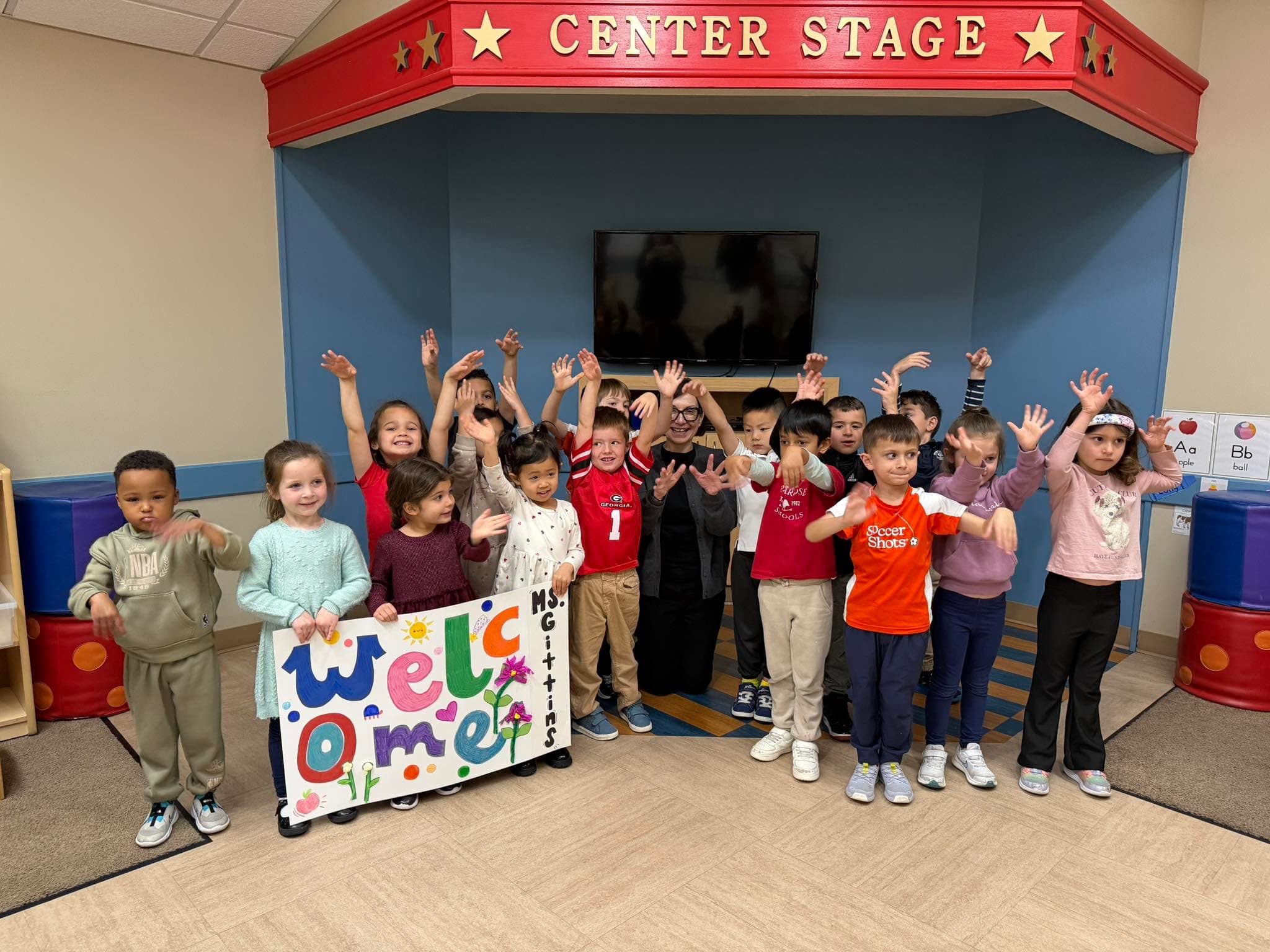 children standing with an adult holding a welcome sign