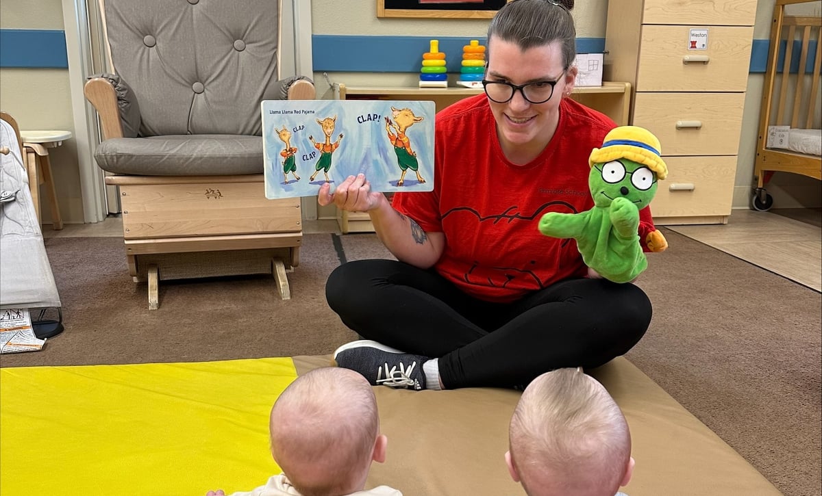 Teacher Janessa reading a picture book with puppet to two young infants at Primrose School of Eagan infant daycare in Eagan, MN
