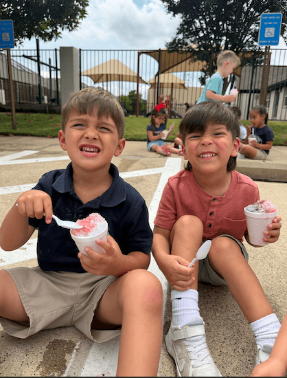 2 boys eating snowcones from snowies to kick off summer at primrose school of hickory creek