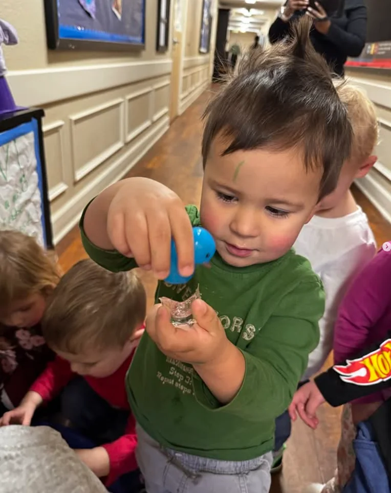 Toddler holding a small blue rubber duck during a classroom activity at Primrose School of Thornton