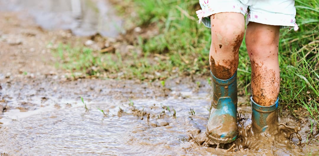 Child's feet stomping in a mud puddle.