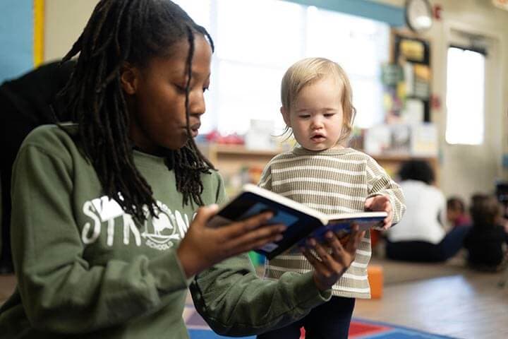 teacher showing a book to toddler child