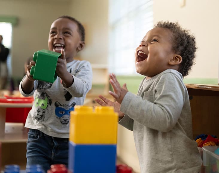 two primrose students laughing while they play with blocks