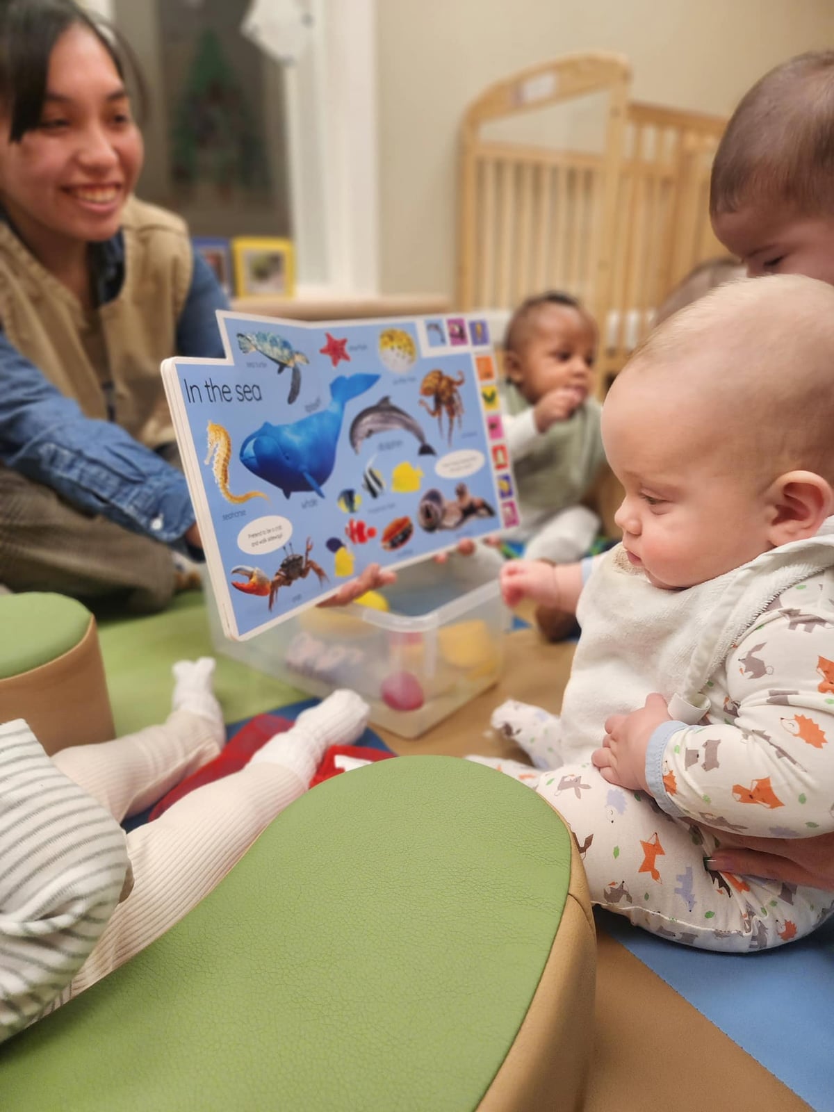 teacher reading a book to four babies