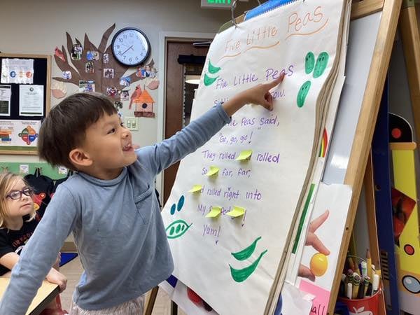 a child at an art easel, working on a literacy lesson
