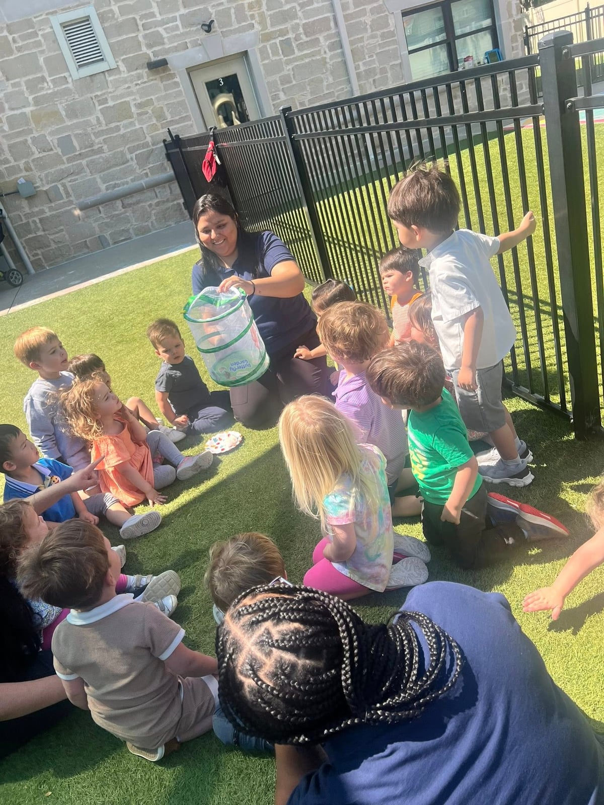 children observing butterflies on a playground with their teachers