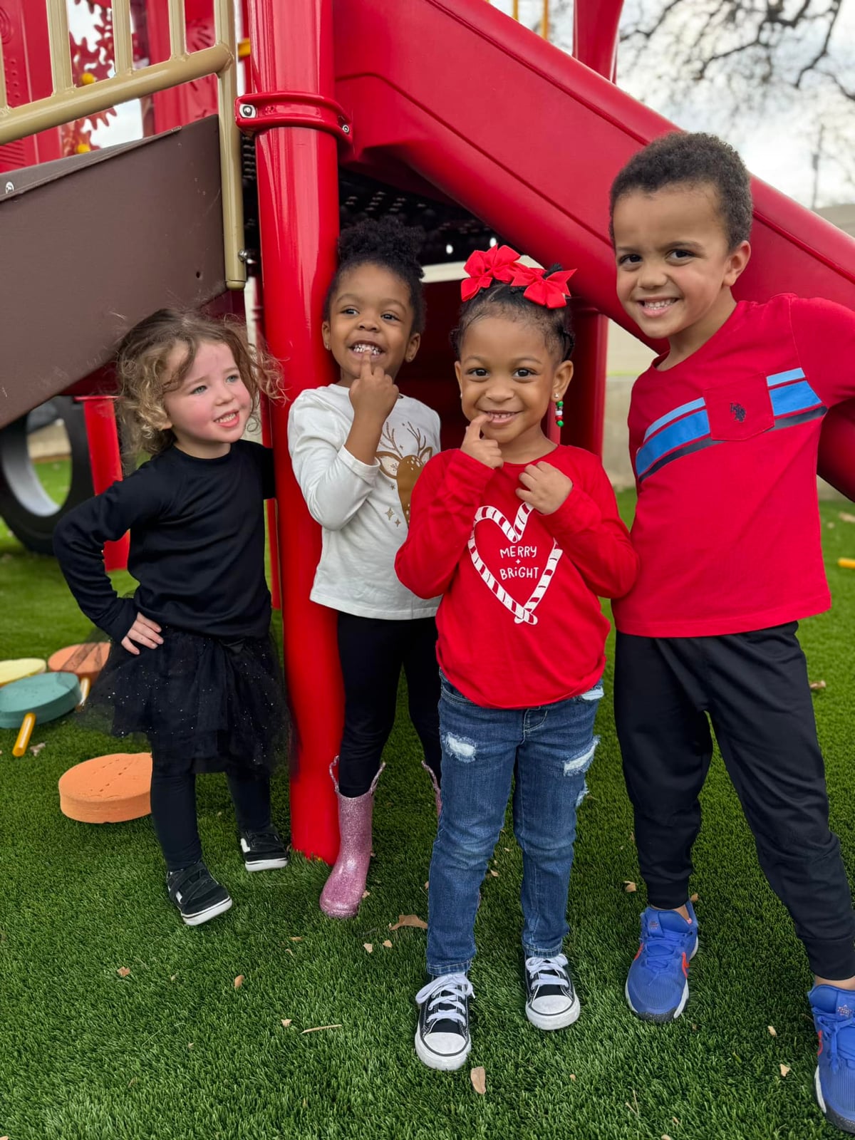 four children smiling on a playground