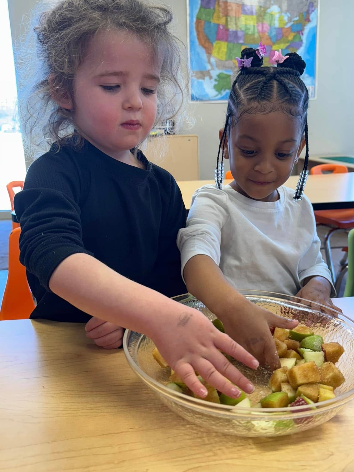 two children mixing a fruit salad