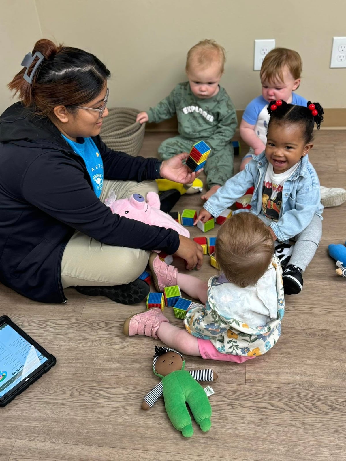 four children playing with stacking blocks with their teacher