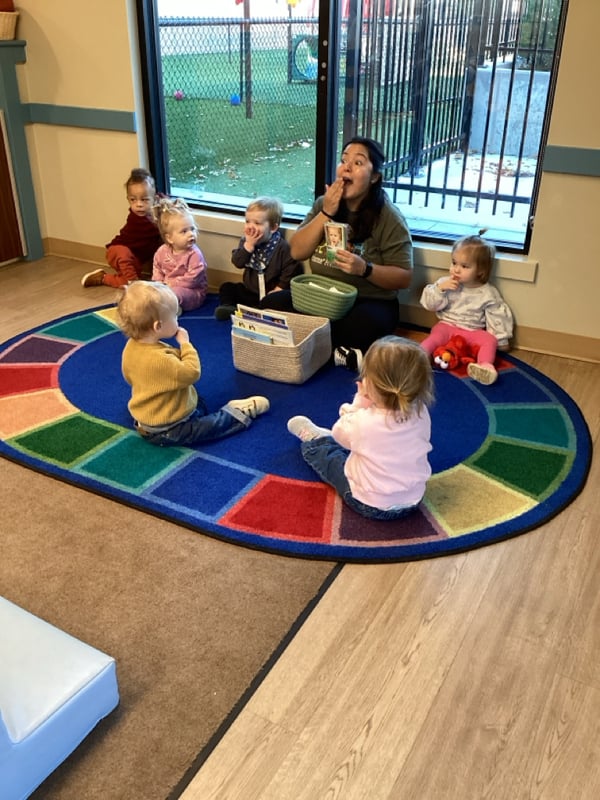 children sitting in circle looking at teacher