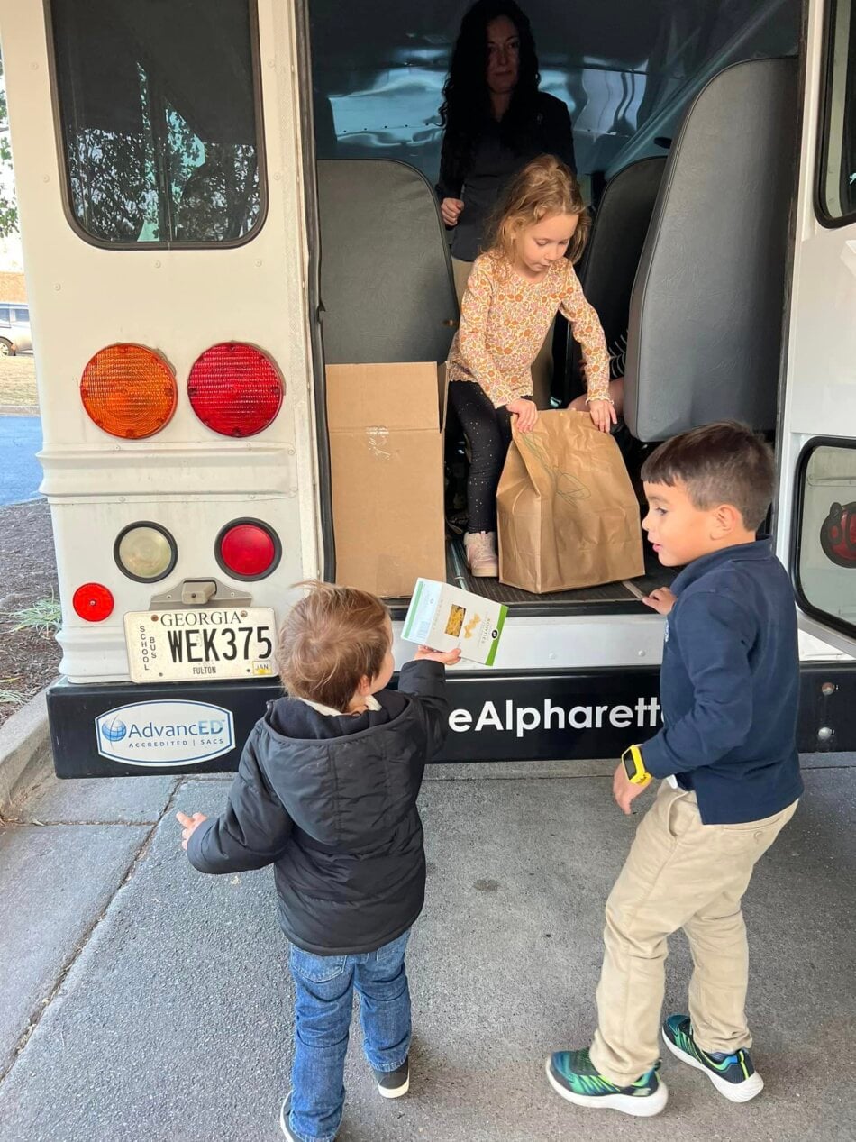 children loading canned goods onto a bus for donation