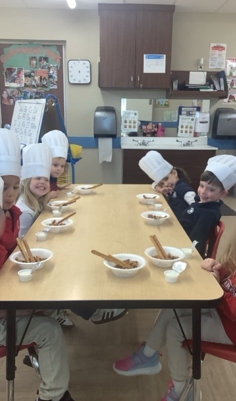 children at a table with chef hats