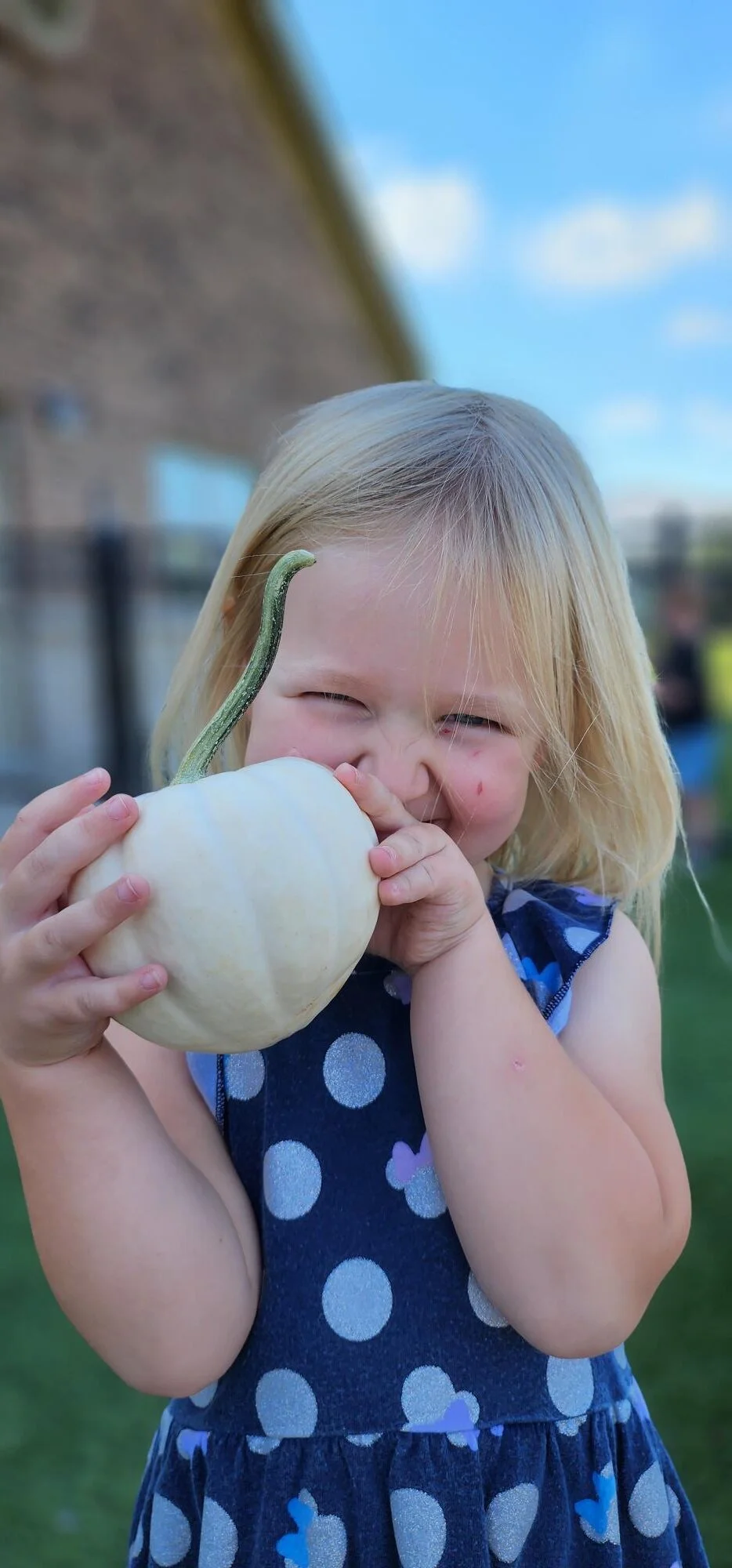 Smiling child holding a pumpkin in the garden where the children learn hands on about living plants