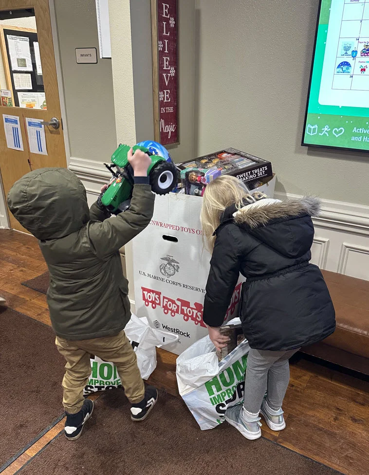 Children from Primrose School of Eagan excitedly donating new toys to the U.S. Marine Corps Reserve Toys for Tots collection box, supporting holiday giving and community service in Eagan, Minnesota.