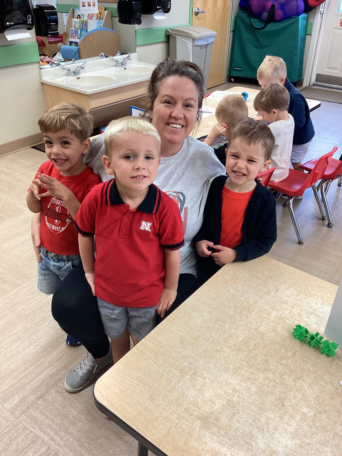 A teacher pictured with three students in red to celebrate Nebraska Cornhuskers football team.
