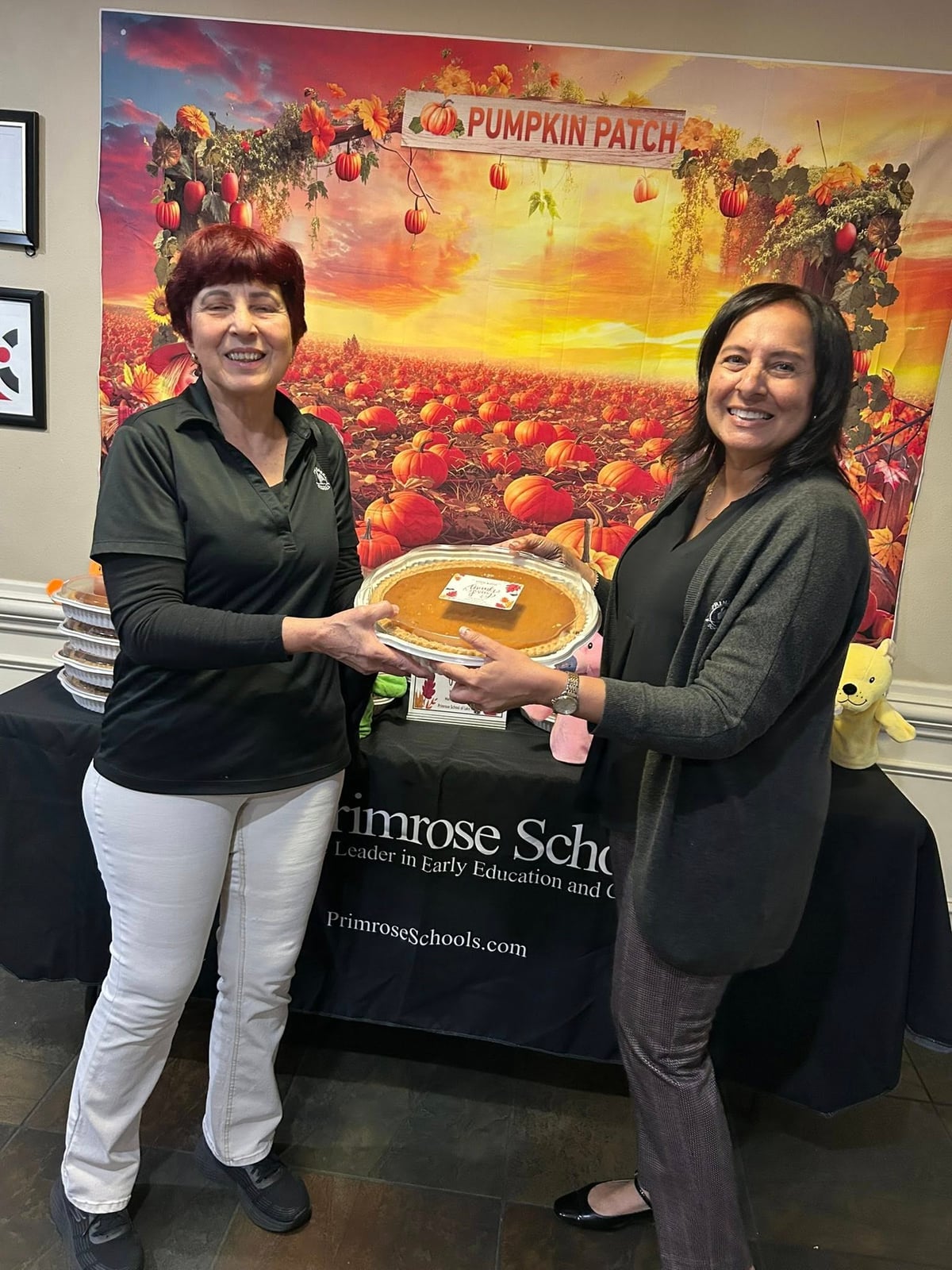 two women holding a pumpkin pie