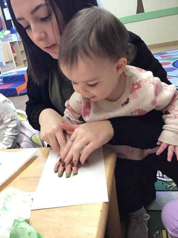 Child doing a handprint art with a teacher