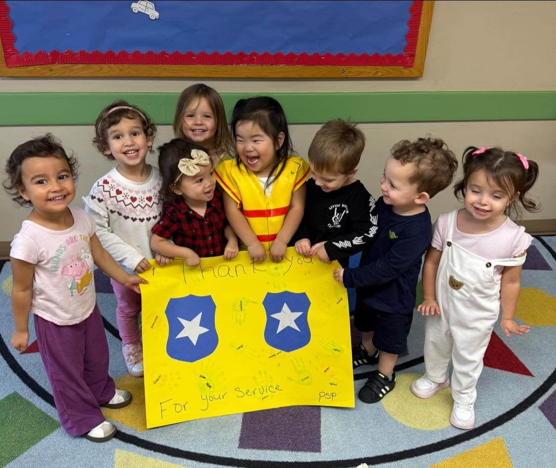 children standing on a rug holding yellow poster