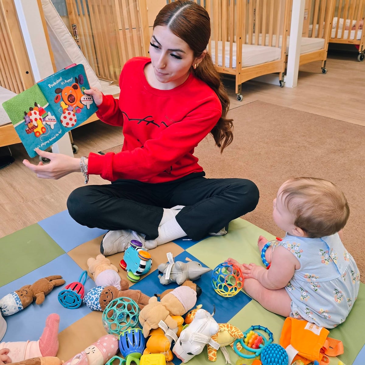 Infant Teacher reading a book to babies on the mat in Infant classroom at Primrose School in Fort Worth.