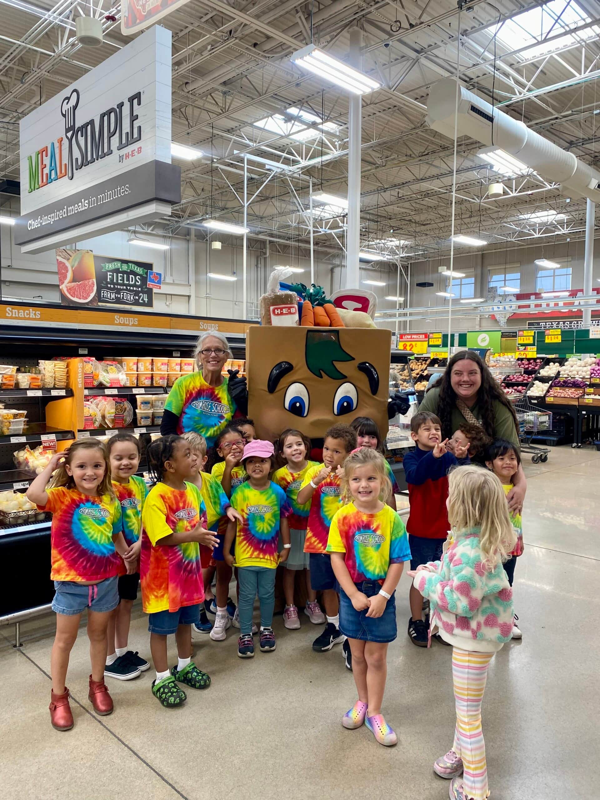 Pre-K students from Primrose School of Four Points posing with H-E-B Buddy and their teachers during a field trip to H-E-B in Austin, Texas