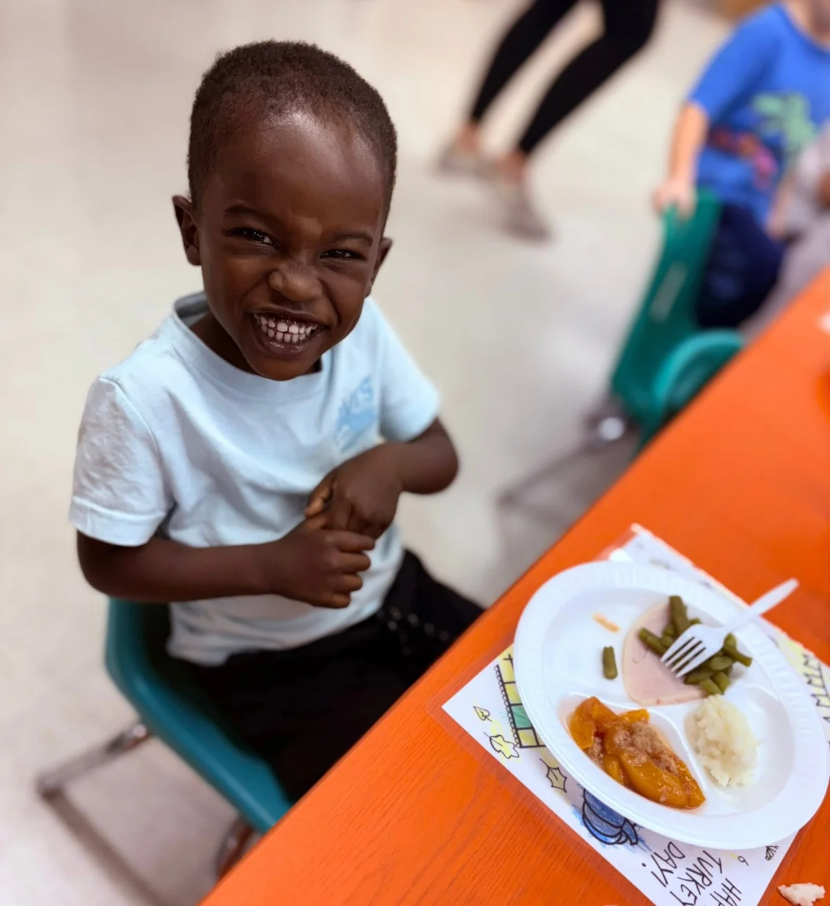 Child smiling in front of a Thanksgiving plate of food