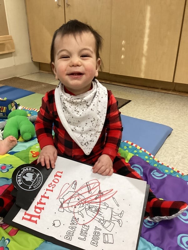 baby boy holding a paper with scribbles on it