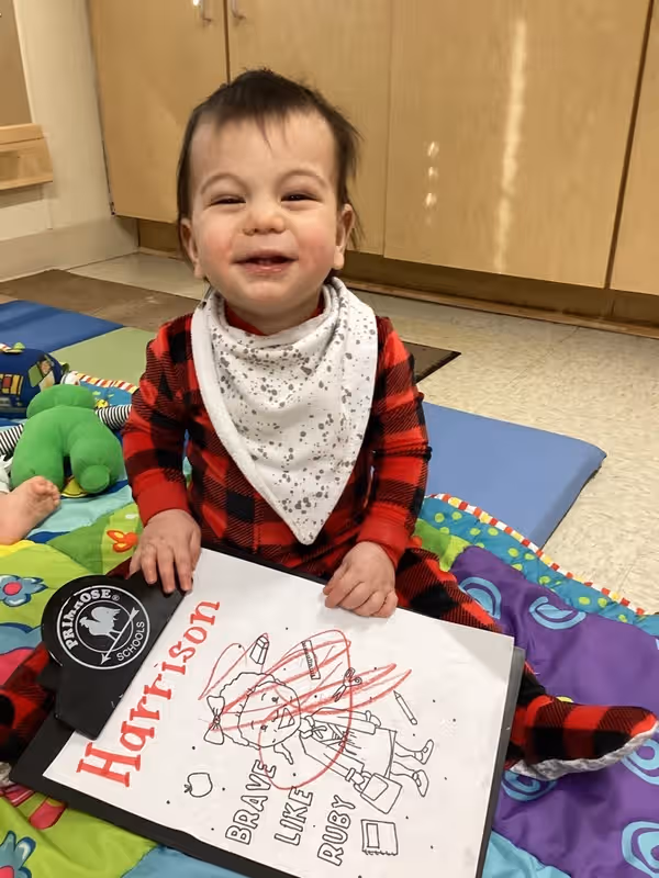 baby boy holding a paper with scribbles on it