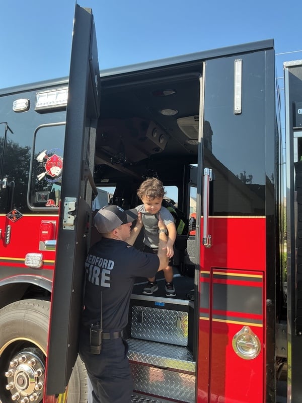little boy being lifted out of a firetruck by a firefighter