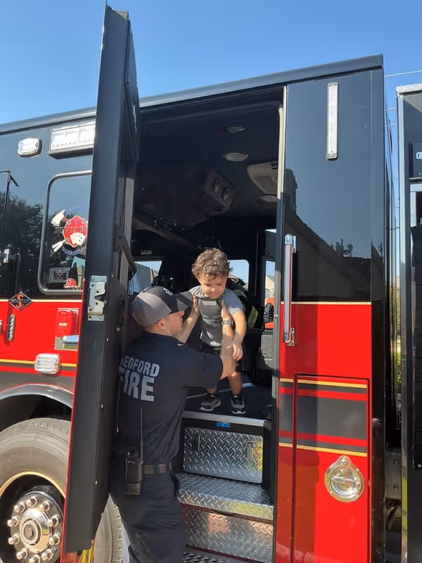 little boy being lifted out of a firetruck by a firefighter