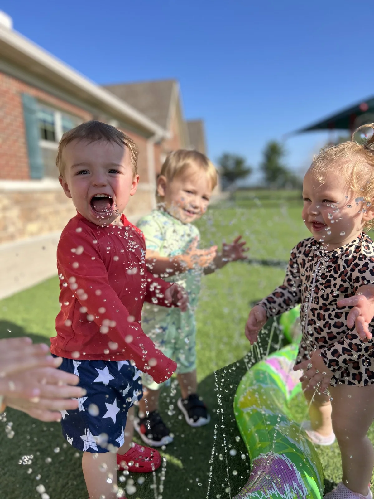 Toddlers playing in water during splash day.