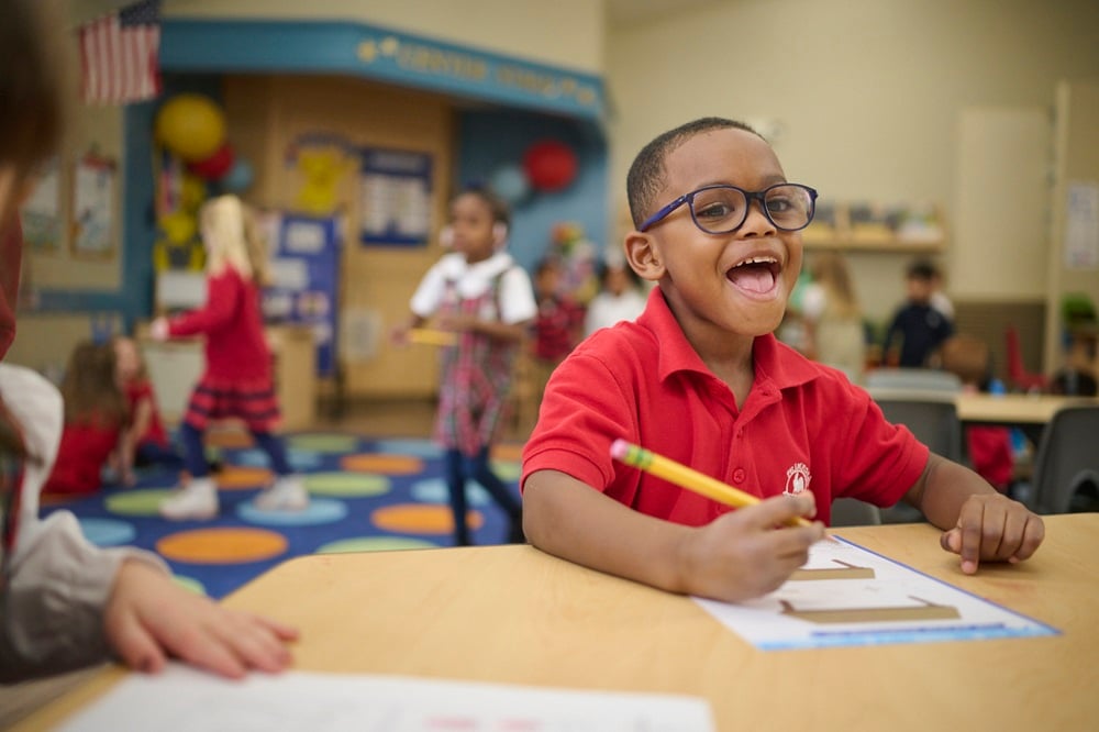 child smiling while completing a worksheet