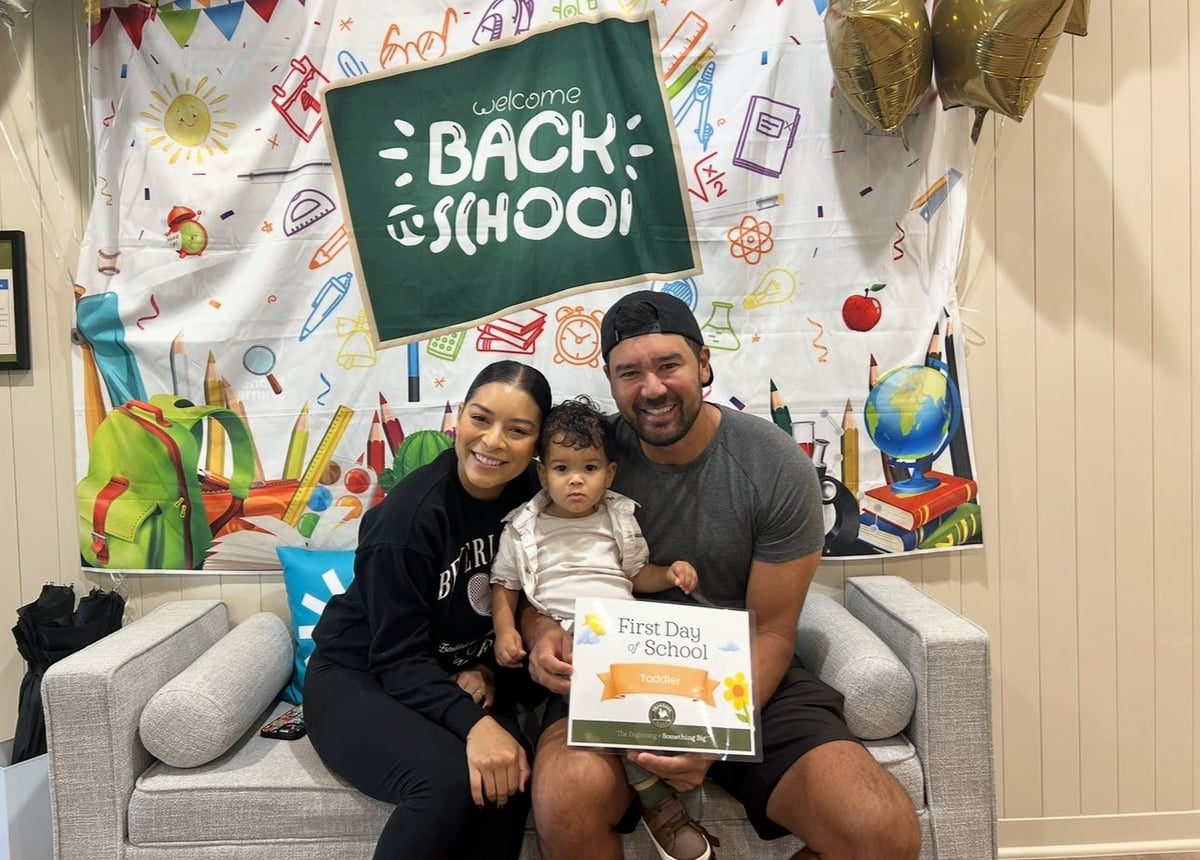 woman and man with little boy on lap and a back to school banner sitting on a couch